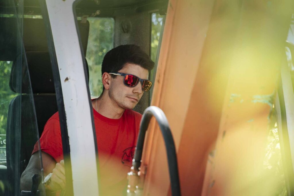 Artisan avec des lunettes de soleil entrain de conduire un engin de chantier